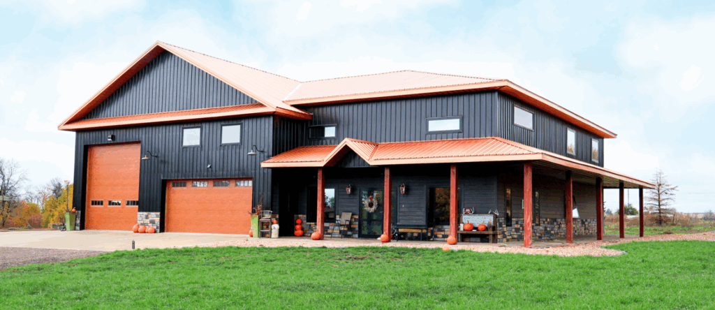 Reaves Buildings Barndominium with a covered porch, horizontal rectangle windows, an oversized garage door and 2 car garage door with dark gray siding and rust-colored roof and accents.
